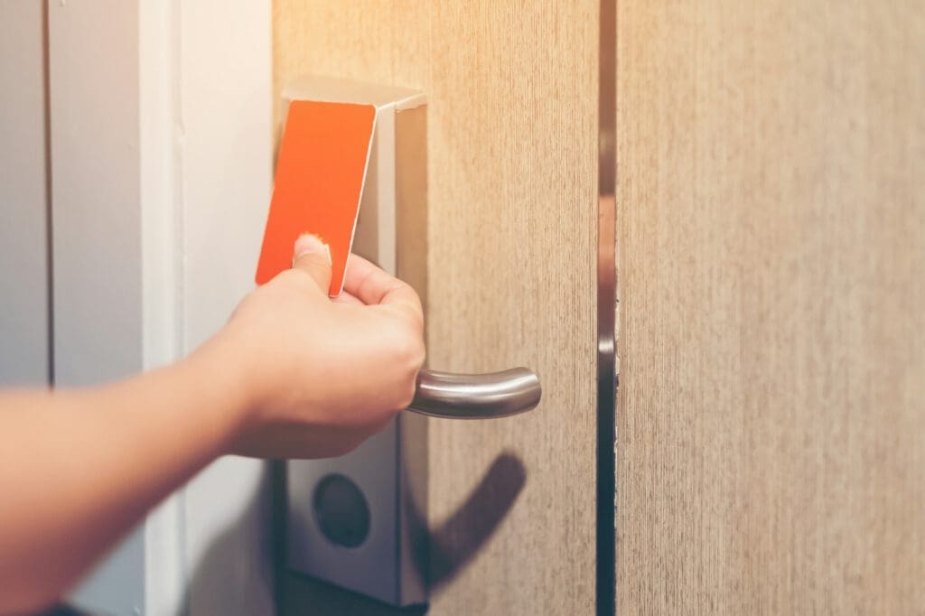 Closeup hand girl opens the door Hotel with electronic card lock on wooden door. Security.